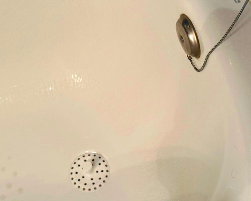 Close-up of a bathtub drain with a metal faucet handle.